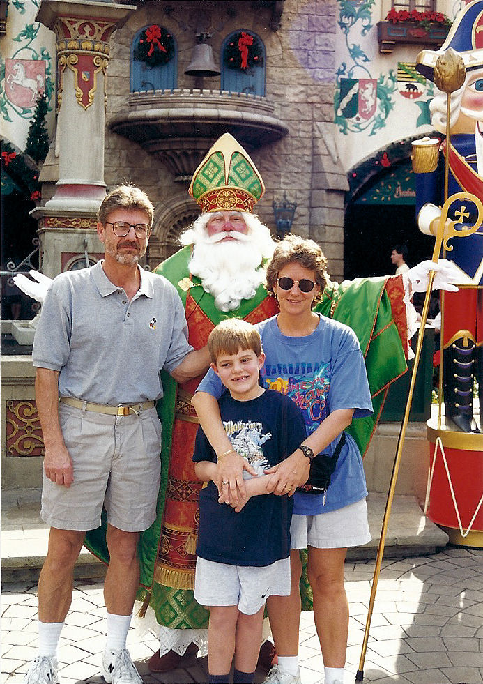 My mom, my dad, and I in the Germany Pavilion at EPCOT at Christmas time posing with St. Nicholas.